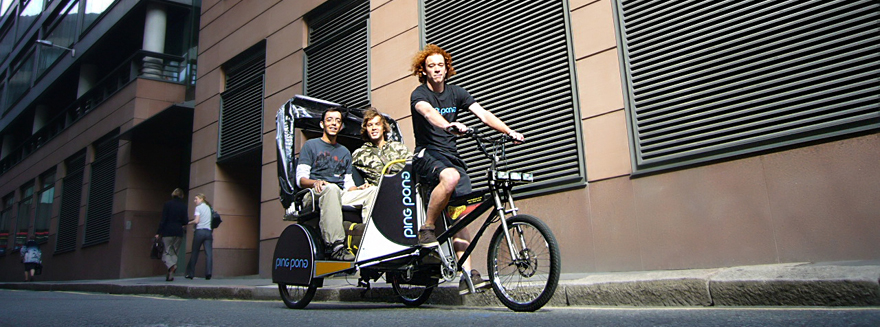 Two male passengers posing, seated at the back of a Bugbugs pedicab